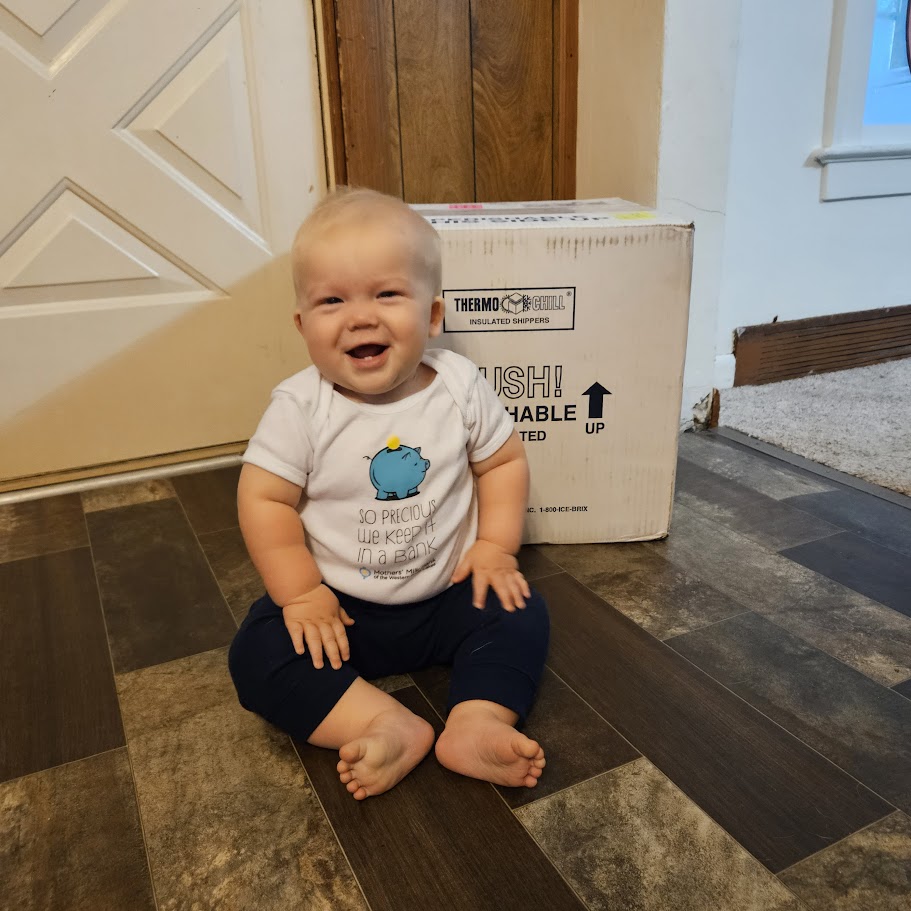 baby in front of donor milk shipping container