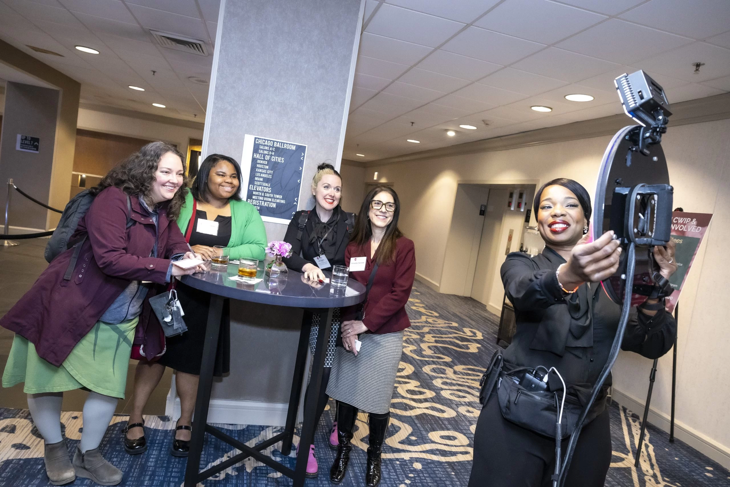 Four Women at a table getting their picture taken with a ring camera