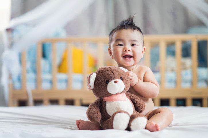 Happy baby sit with teddy bear Baby sitting with teddy bear in bedroom